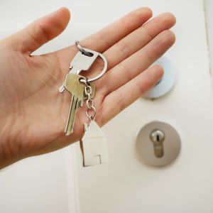 A picture of a hand holding a set of keys with a house shaped key ring