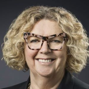 lady's face with blonde curly hair and leopard print glasses