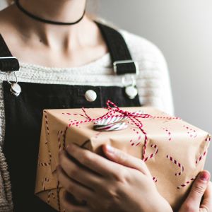 girl hugging a gift wrapped in christmas paper and string to her chest