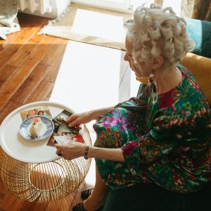 Older woman sitting at coffee table looking at family photographs
